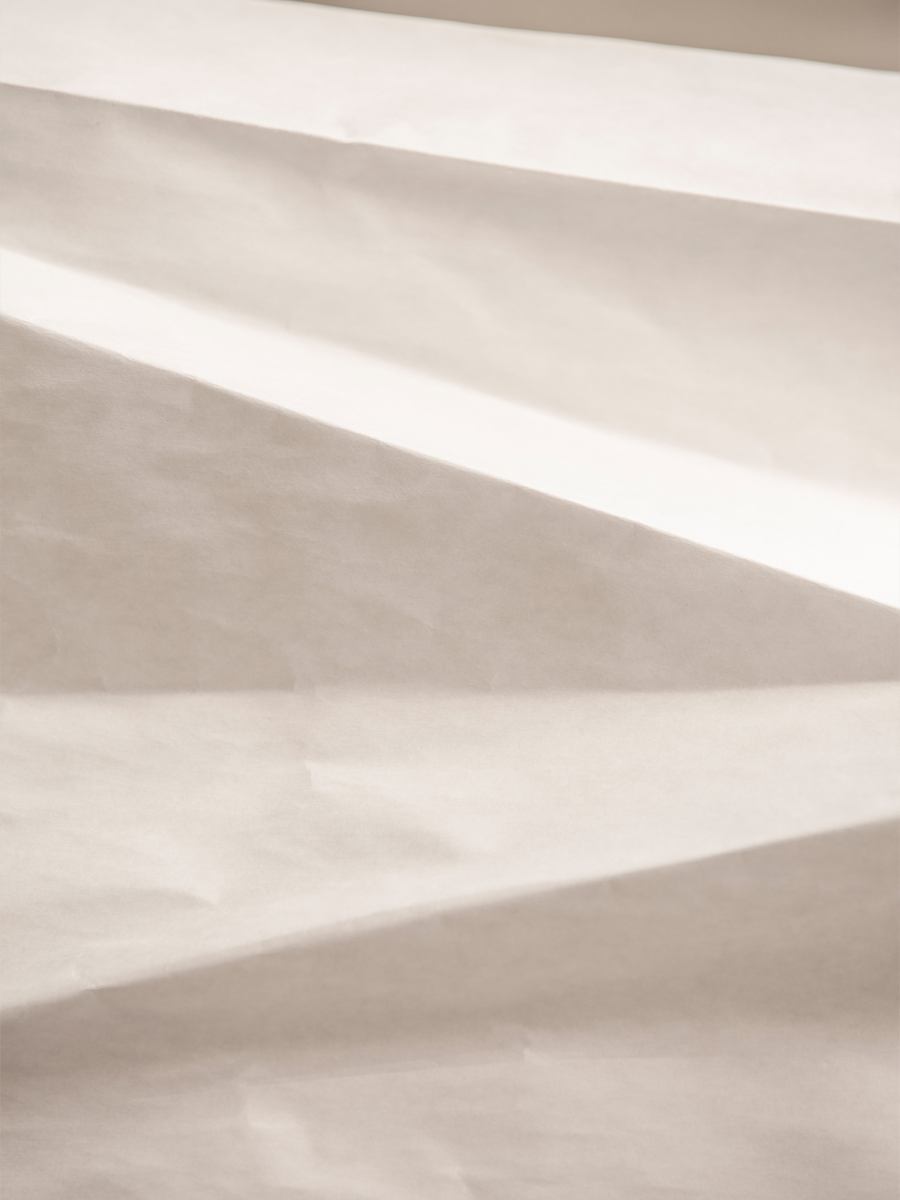 Fotografie von Lichtreflexen auf zerknittertem Papierhintergrund.