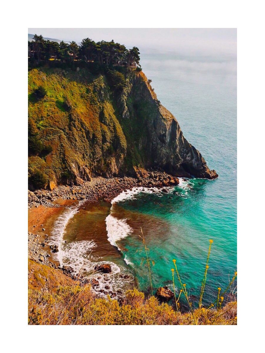 Fotografie einer Bucht mit klarem, blauem Wasser und grünen Klippen.