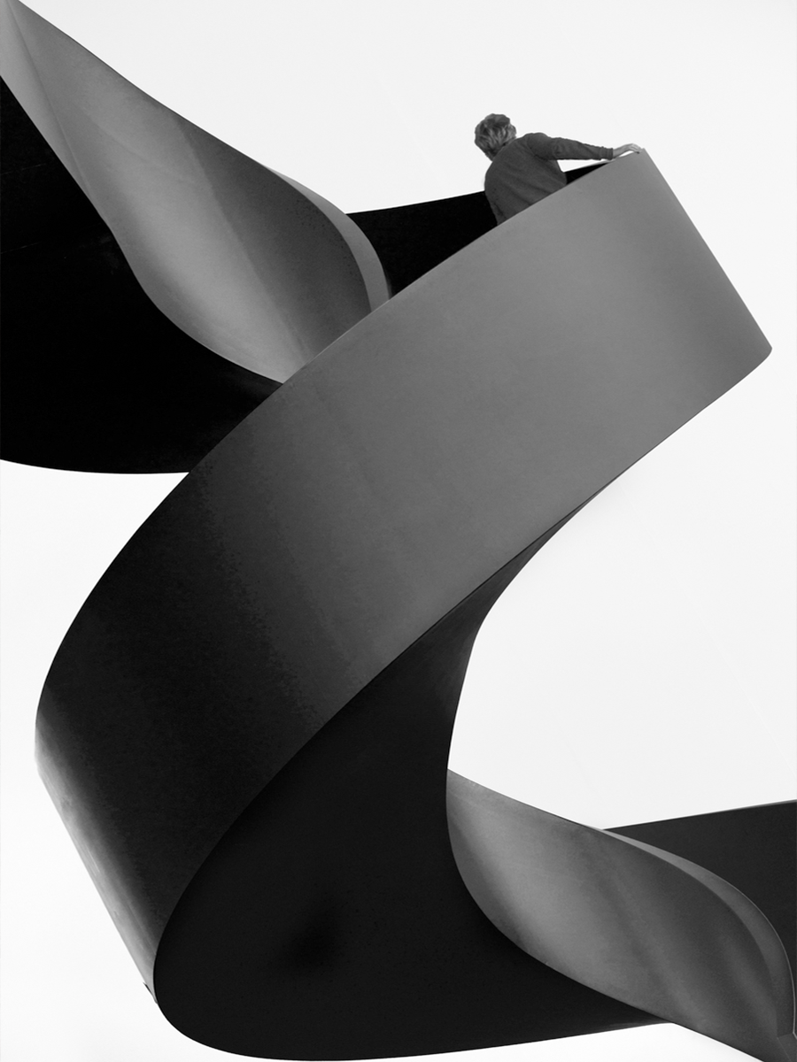 Schwarz-weiße Fotografie einer spiralförmigen Struktur mit einer Person darauf.