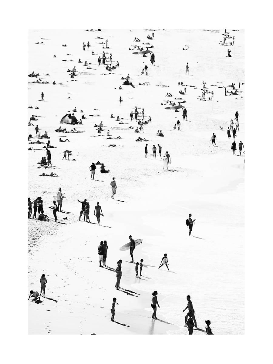 Schwarz-weiß-Fotografie von einem belebten Strand mit vielen Menschen.