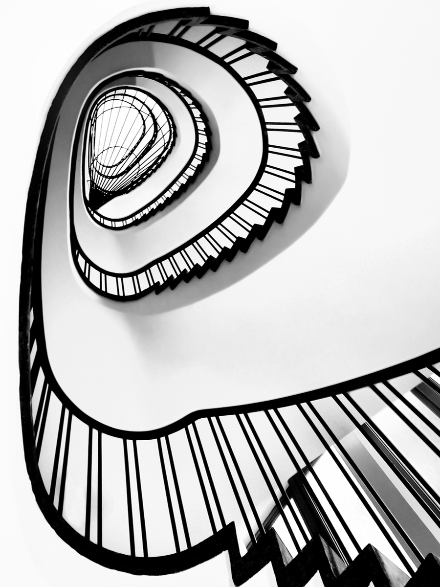 Schwarz-weiß-Fotografie einer spiralförmigen Wendeltreppe.