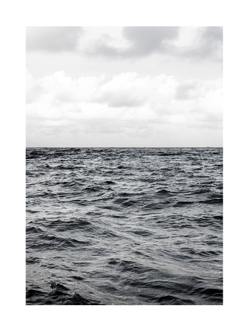 Schwarz-weiß-Fotografie von Wellen auf dem Meer mit bewölktem Himmel.