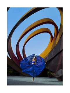 Ballerina in blauem Kleid tanzt vor moderner abstrakter Architektur.