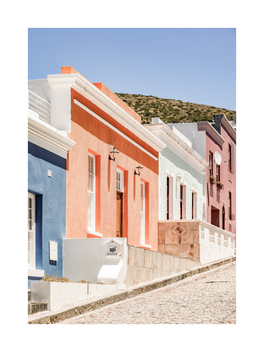 Bunte Häuserreihe im Viertel Bo-Kaap mit blauem Himmel im Hintergrund.