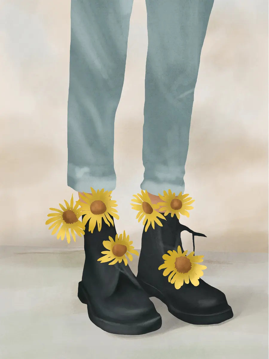 Beine in hellblauen Jeans und schwarzen Boots, die mit gelben Sonnenblumen geschmückt sind.