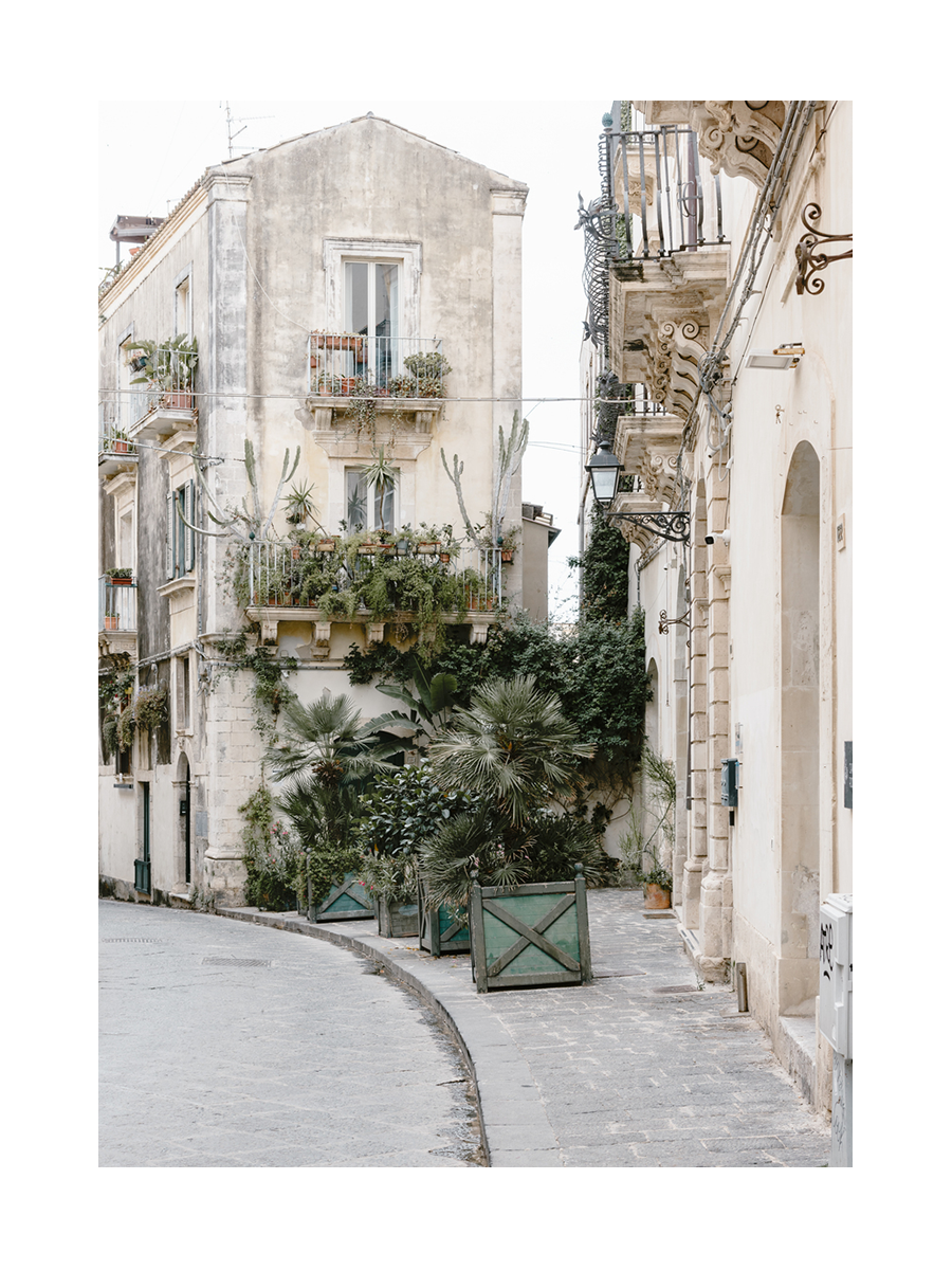 Fotografie einer sizilianischen Straße mit einem Gebäude voller Pflanzen und Kakteen.