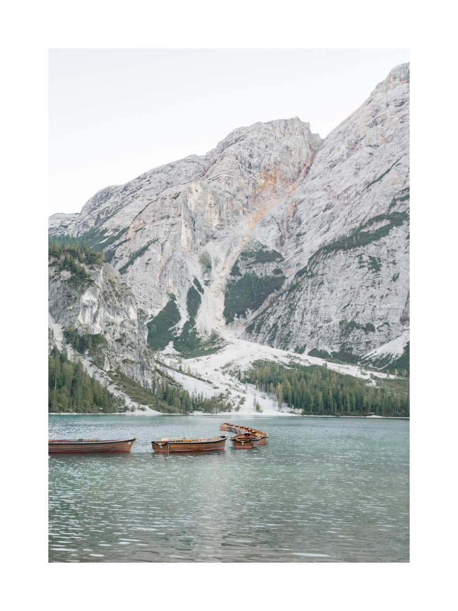 Fotografie von Booten auf einem See mit großen Bergen im Hintergrund.