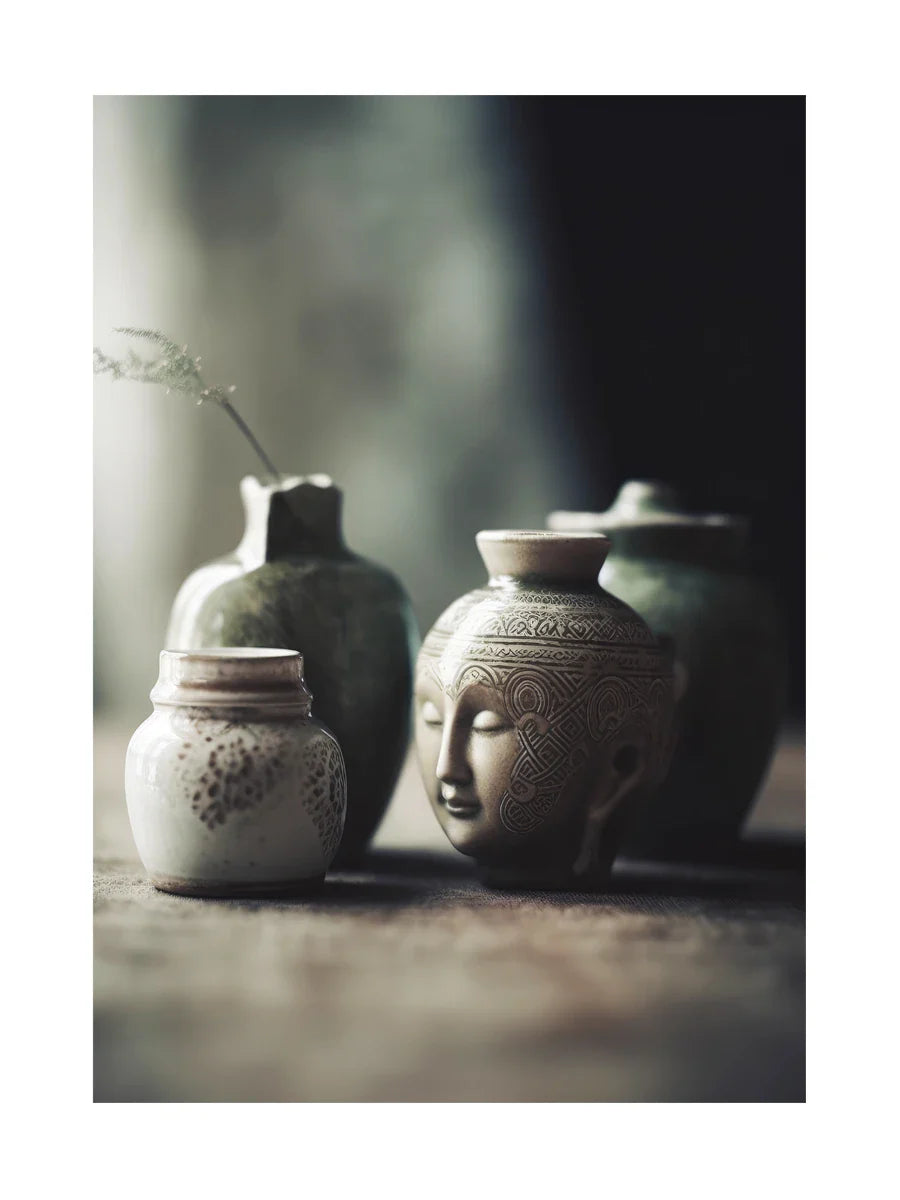 Sammlung von Keramikvasen, darunter eine mit einem Buddha-Gesicht, auf unscharfem Hintergrund.