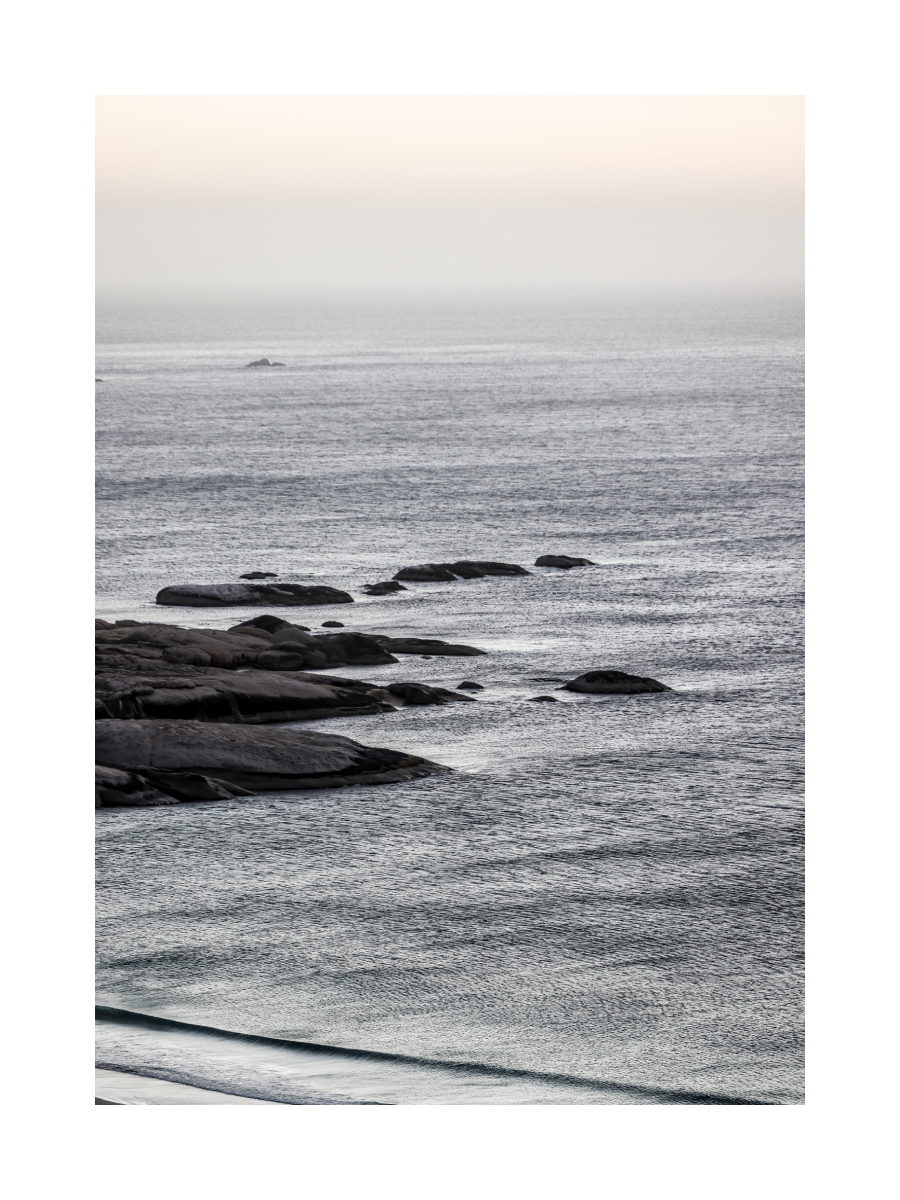 Fotografie von Felsen im Meer mit hellem Himmel im Hintergrund.