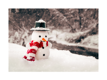 Ein Mini-Schneemann mit gestreiftem Hut und Schal im Schnee.