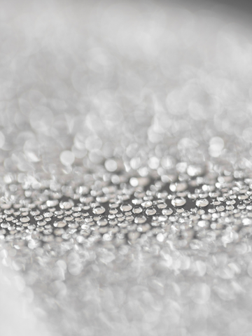 Nahaufnahme von Wassertropfen in unscharfem Grauton.