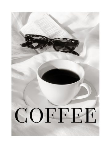 Eine Tasse Kaffee auf einem Bett mit einer Sonnenbrille und einem Buch daneben.