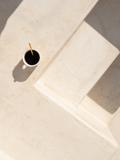 Eine Tasse Kaffee auf einer hellen Treppe mit Schatten.