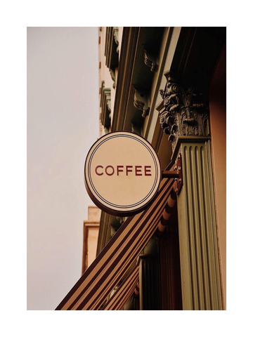 Fotografie eines antiken Coffee-Shop-Schildes an einer verzierten Gebäudefassade.