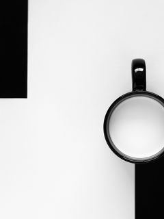 Fotografie von zwei Tassen, eine schwarz und eine weiß, auf einem schwarz-weißen Hintergrund.