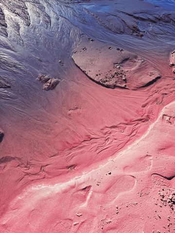 Fotografie von rosa Sand und violettem Wasser.