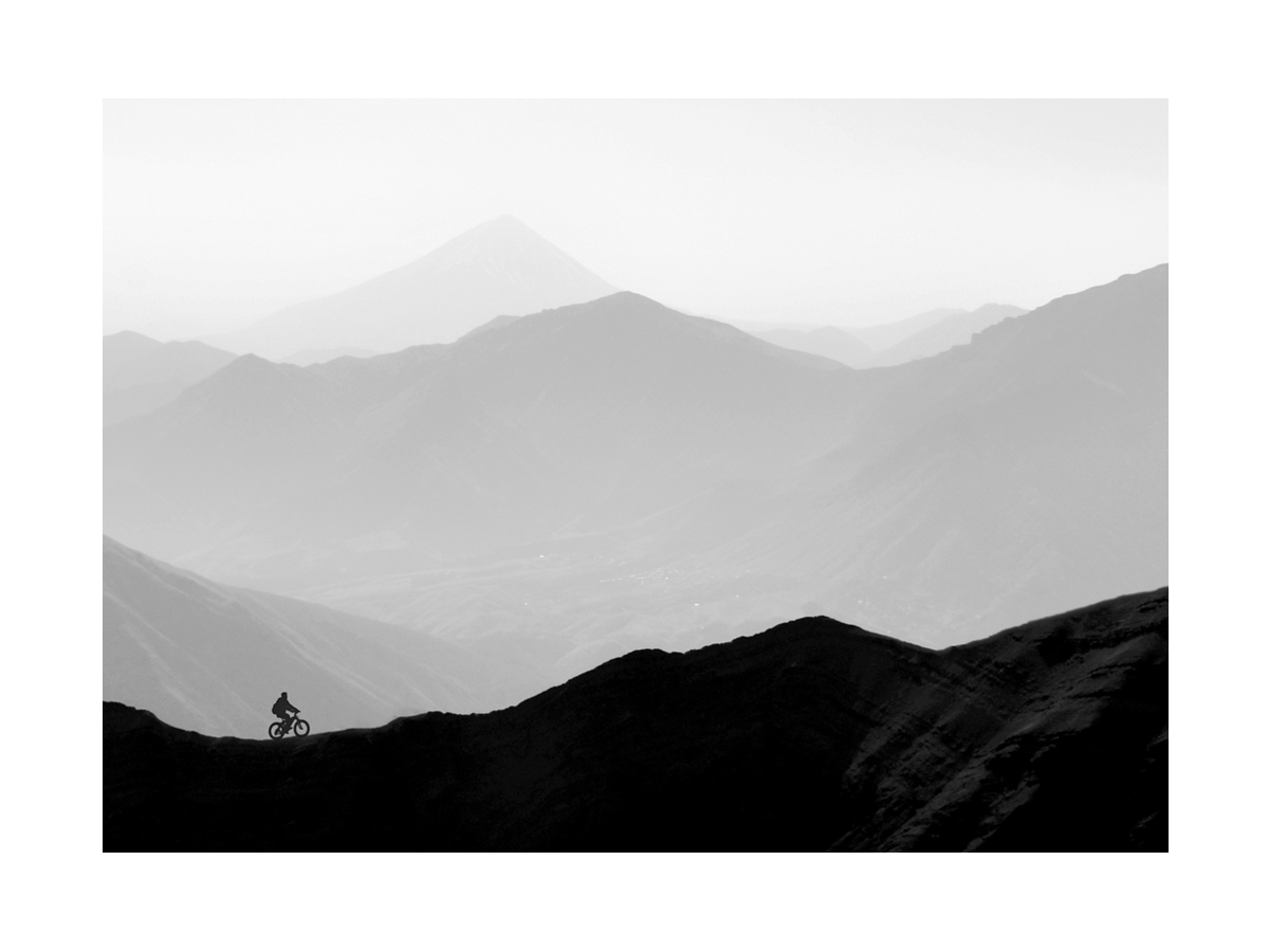 Schwarz-weißes Poster eines Radfahrers in einer Berglandschaft.