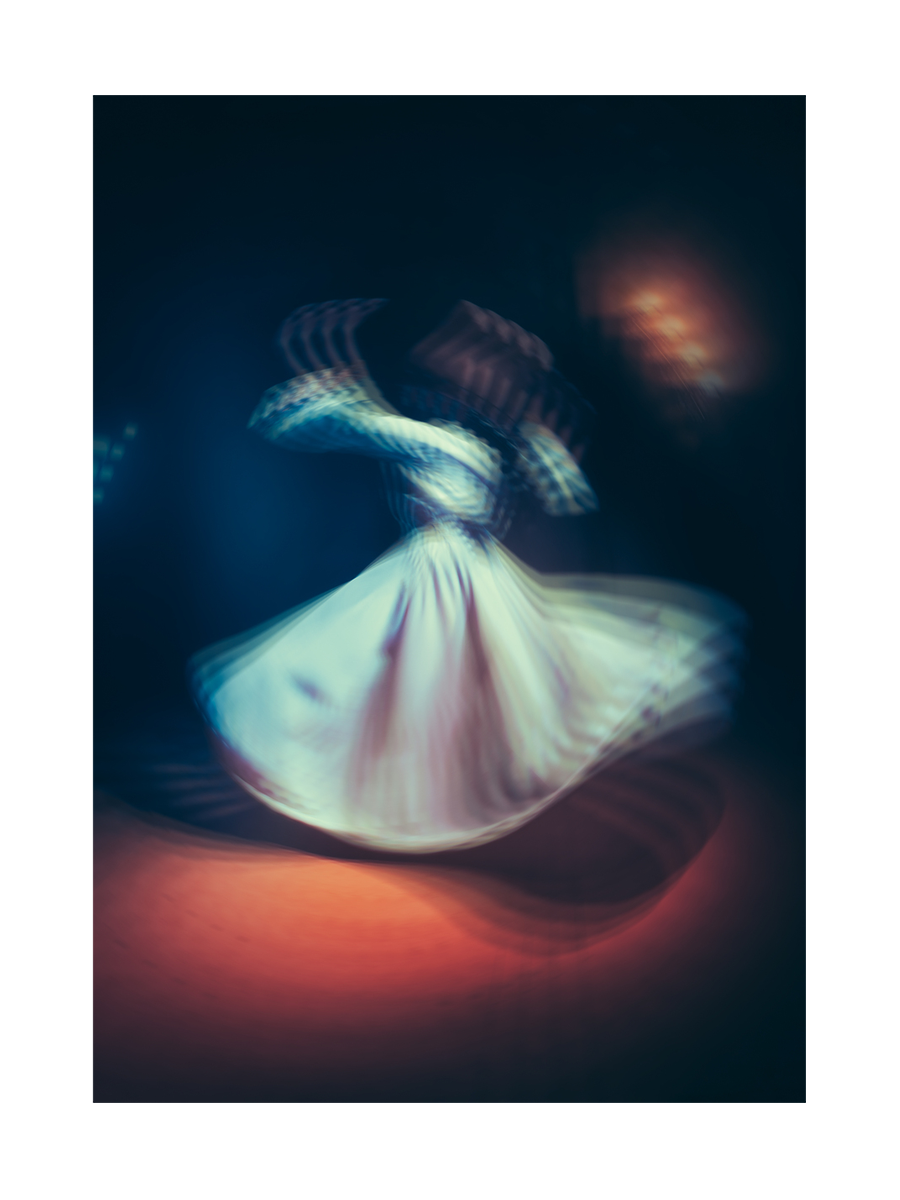 Verschwommene Darstellung eines tanzenden Derwischs in Bewegung mit dunklem Hintergrund.