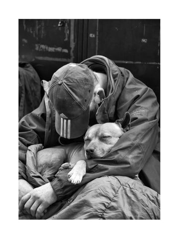 Schwarz-Weiß-Fotografie eines schlafenden Mannes mit einem Hund in seinen Armen.