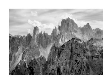Schwarz-weiß-Fotografie der Dolomiten mit dramatischen Berggipfeln und Himmel.