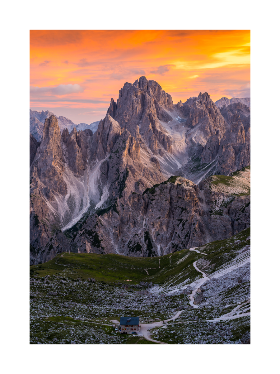 Dolomiten bei Sonnenuntergang mit dramatischen Berggipfeln und orangefarbenem Himmel.