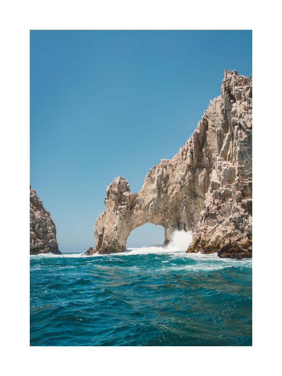 Fotografie von El Arco, einer Felsformation in Cabo San Lucas, umgeben von türkisfarbenem Wasser und blauem Himmel.