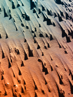 Textur von Sand in einer Farbpalette von Orange bis Blau.