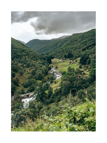 Landschaftsfotografie eines grünen Tals mit Bach und Häusern im Fjordland.