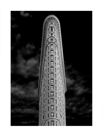 Schwarzweiß-Fotografie des Flatiron Building vor einem dunklen Himmel.