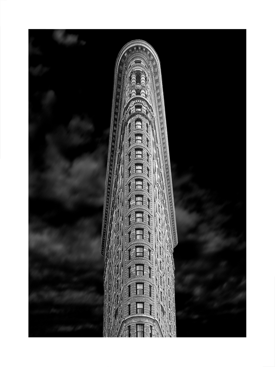 Schwarzweiß-Fotografie des Flatiron Building vor einem dunklen Himmel.
