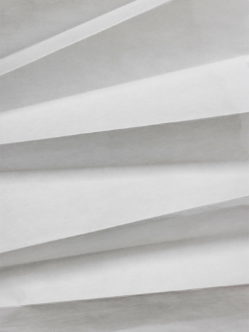 Fotografie eines abstrakten Faltenmusters in Weiß und Grau.