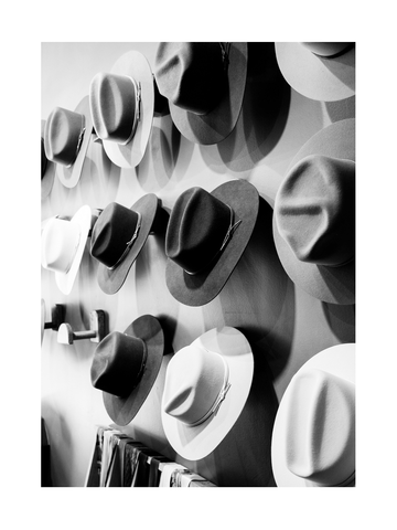 Schwarz-Weiß-Fotografie von Hüten an einer Wand.