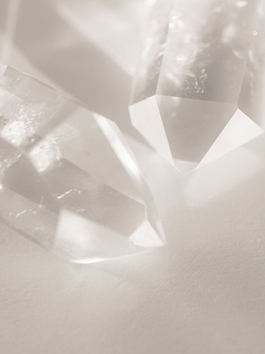 Fotografie von klaren Kristallen auf beigem Hintergrund.