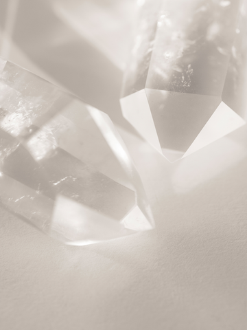 Fotografie von klaren Kristallen auf beigem Hintergrund.