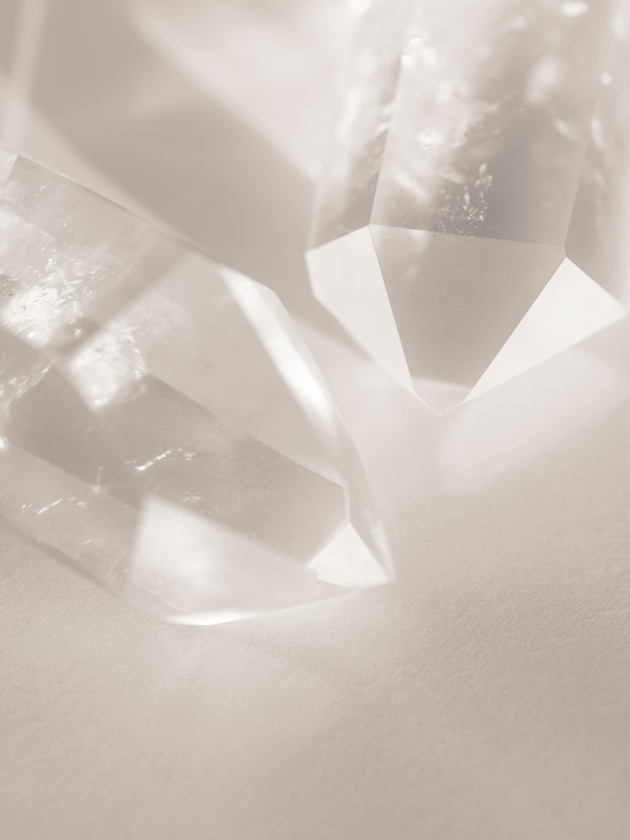 Fotografie von klaren Kristallen auf beigem Hintergrund.