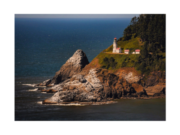 Fotografie des Heceta Head Leuchtturms auf einer felsigen Klippe am Meer.