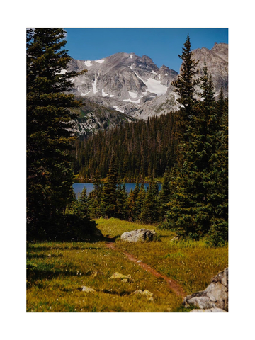 Ein Wanderweg in einer Berglandschaft mit See und schneebedeckten Gipfeln.