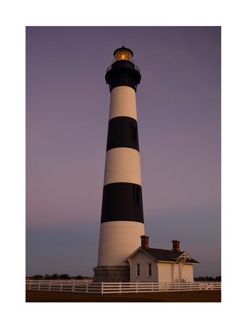 Leuchtturm mit schwarz-weißen Streifen vor einem lila Himmel.