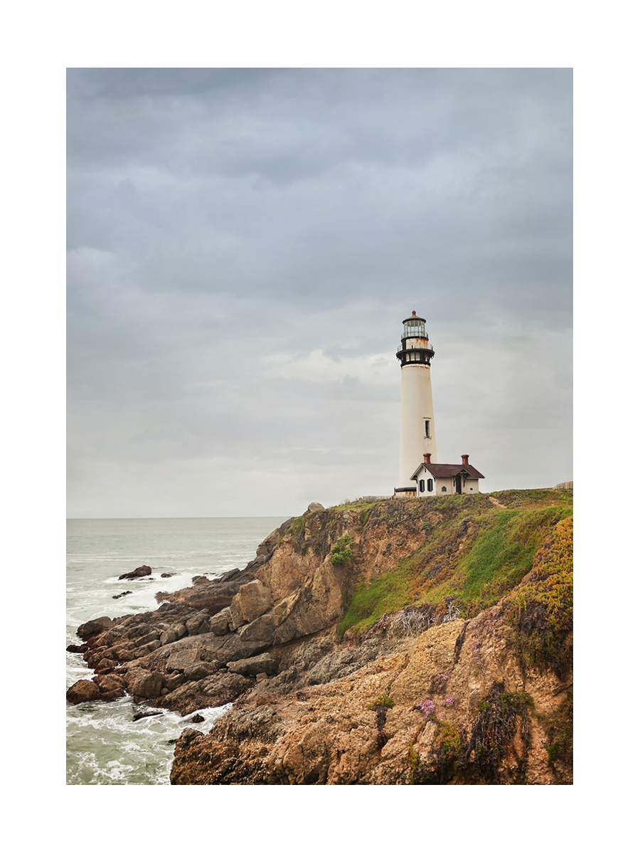 Fotografie eines Leuchtturms auf einer Klippe mit Meer im Hintergrund.