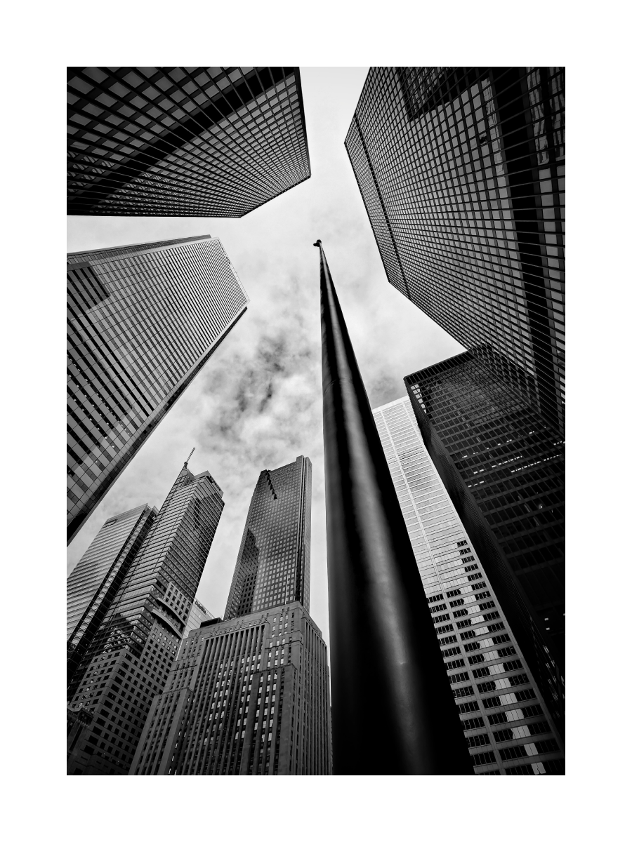 Schwarz-weiß-Fotografie von Wolkenkratzern und einer Statue, von unten aufgenommen.