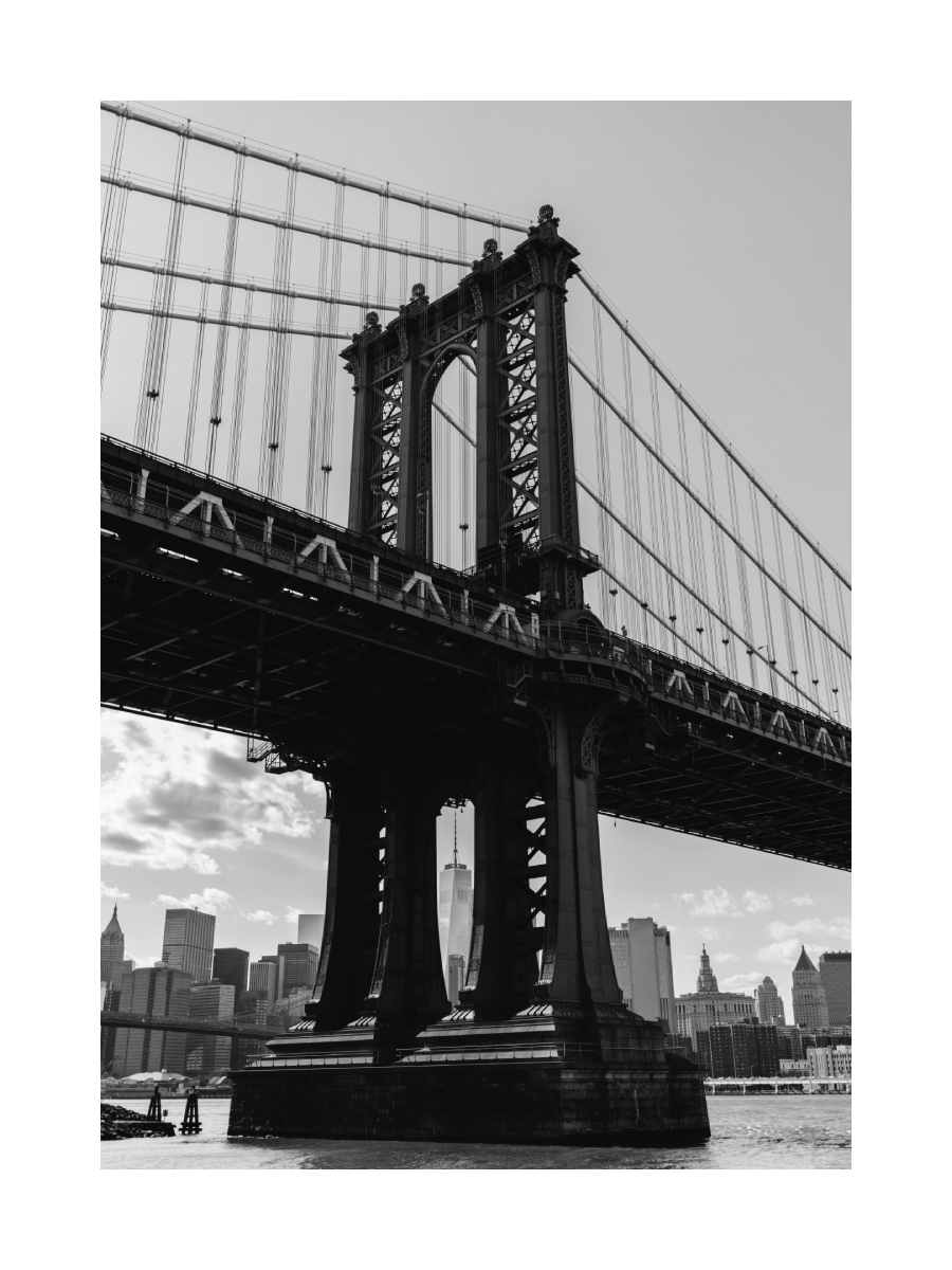 Schwarz-Weiß-Fotografie der Manhattan Bridge mit der Skyline von New York im Hintergrund.