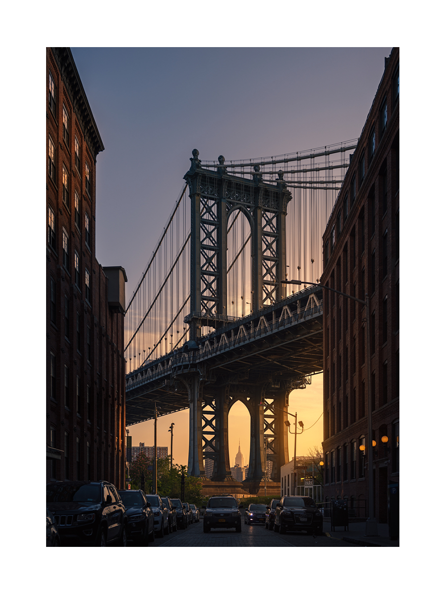 Fotografie der Manhattan Bridge bei Sonnenuntergang mit dem Empire State Building im Hintergrund.