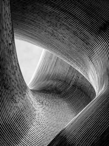 Monochromes Bild einer geschwungenen, abstrakten Architektur mit parallelen Linien.