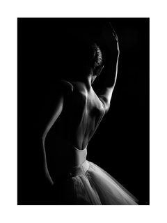 Schwarz-weiß-Fotografie einer Ballerina im Tutu vor schwarzem Hintergrund.