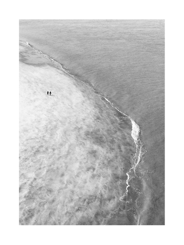 Schwarzweiß-Fotografie von zwei Menschen, die am Strand spazieren.