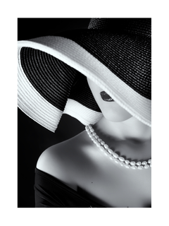 Schwarz-weiß-Fotografie einer Frau mit breitrandigem Hut und Perlenkette.