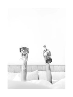 Schwarzweiß-Fotografie von zwei Armen, die ein Weinglas und eine Flasche Aperol halten.