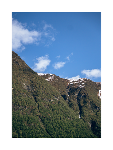 Fotografie der Spitze eines Berges mit blauem Himmel und Wolken im Hintergrund.