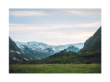 Fotografie von schneebedeckten Bergen mit einem Tal und einem kleinen Dorf im Vordergrund.
