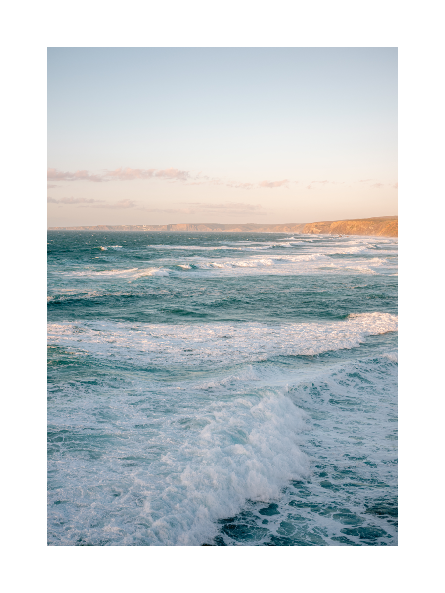 Fotografie des Ozeans mit Wellen und einer Klippe im Hintergrund.